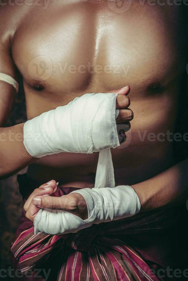o boxeador sentou-se na pedra, amarrou a fita na mão, preparando-se para lutar. foto