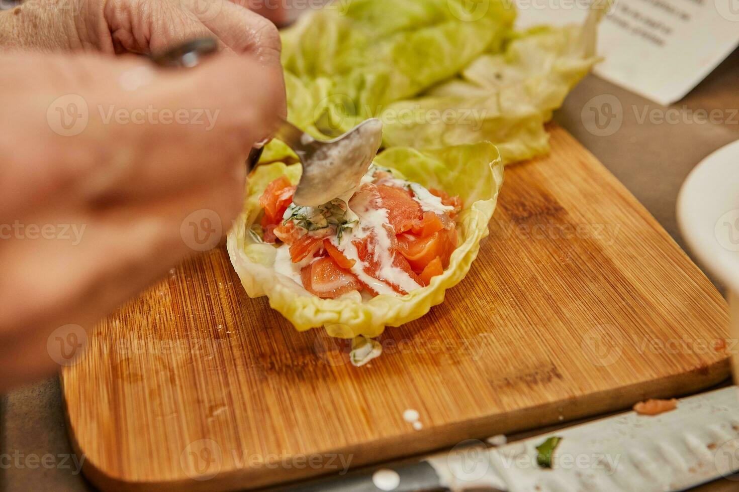 chefe de cozinha faz repolho rolos com salmão, cenouras e molho dentro a cozinha. francês receita foto