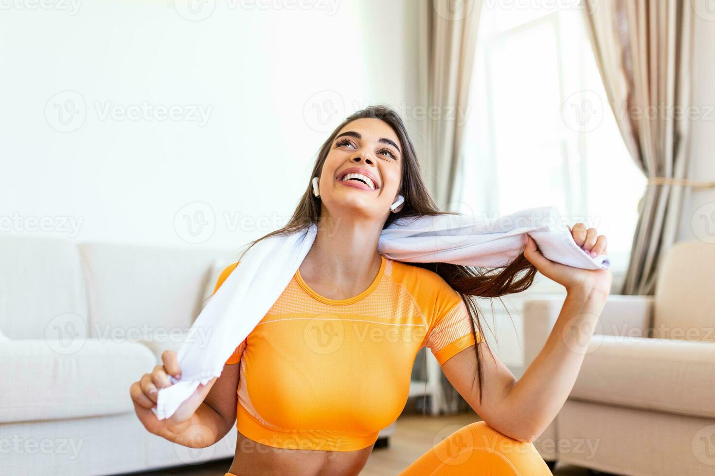 lindo jovem mulher limpando suor com uma toalha, Exausta depois de a diariamente treinamento.atraente jovem mulher levando uma pausa enquanto exercício às lar. foto