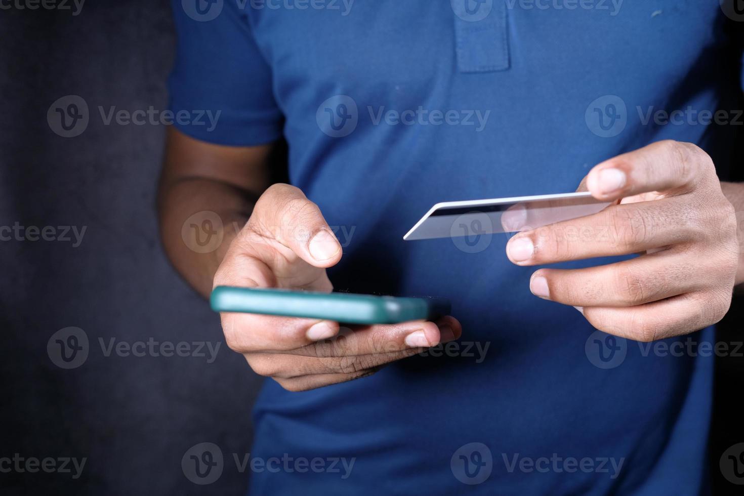 mão de homem segurando cartão de crédito e usando telefone inteligente para fazer compras online foto