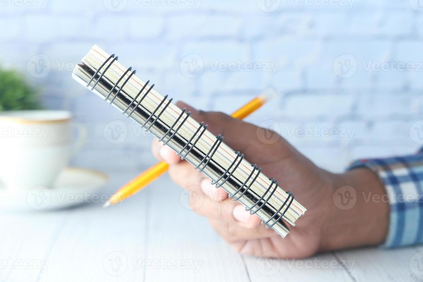 close-up de um homem segurando um bloco de notas foto