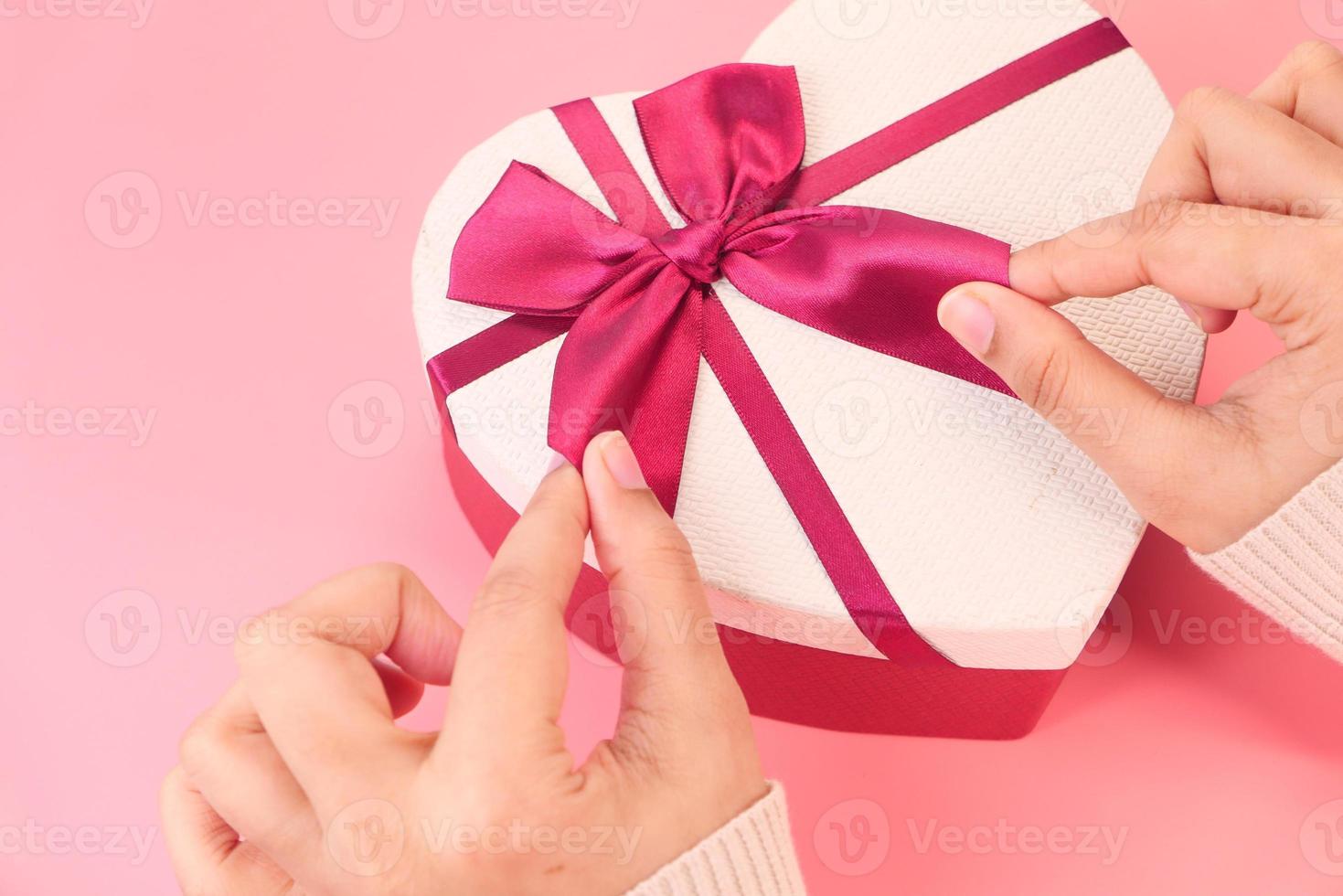 caixa de presente em forma de coração em fundo rosa foto