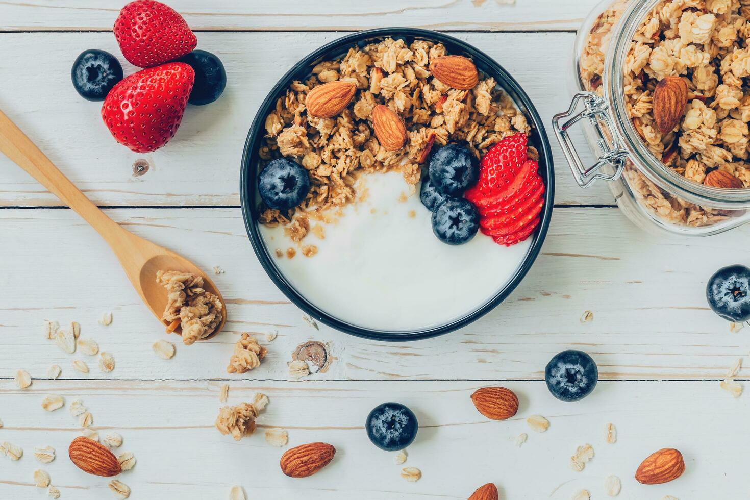 tigela do granola com iogurte, fresco bagas, amoras e noz em madeira mesa. foto