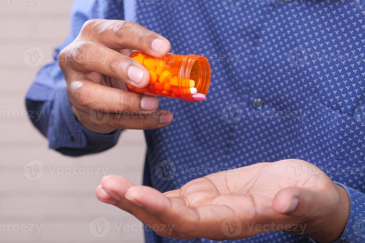 mão do homem segurando um frasco de comprimidos foto