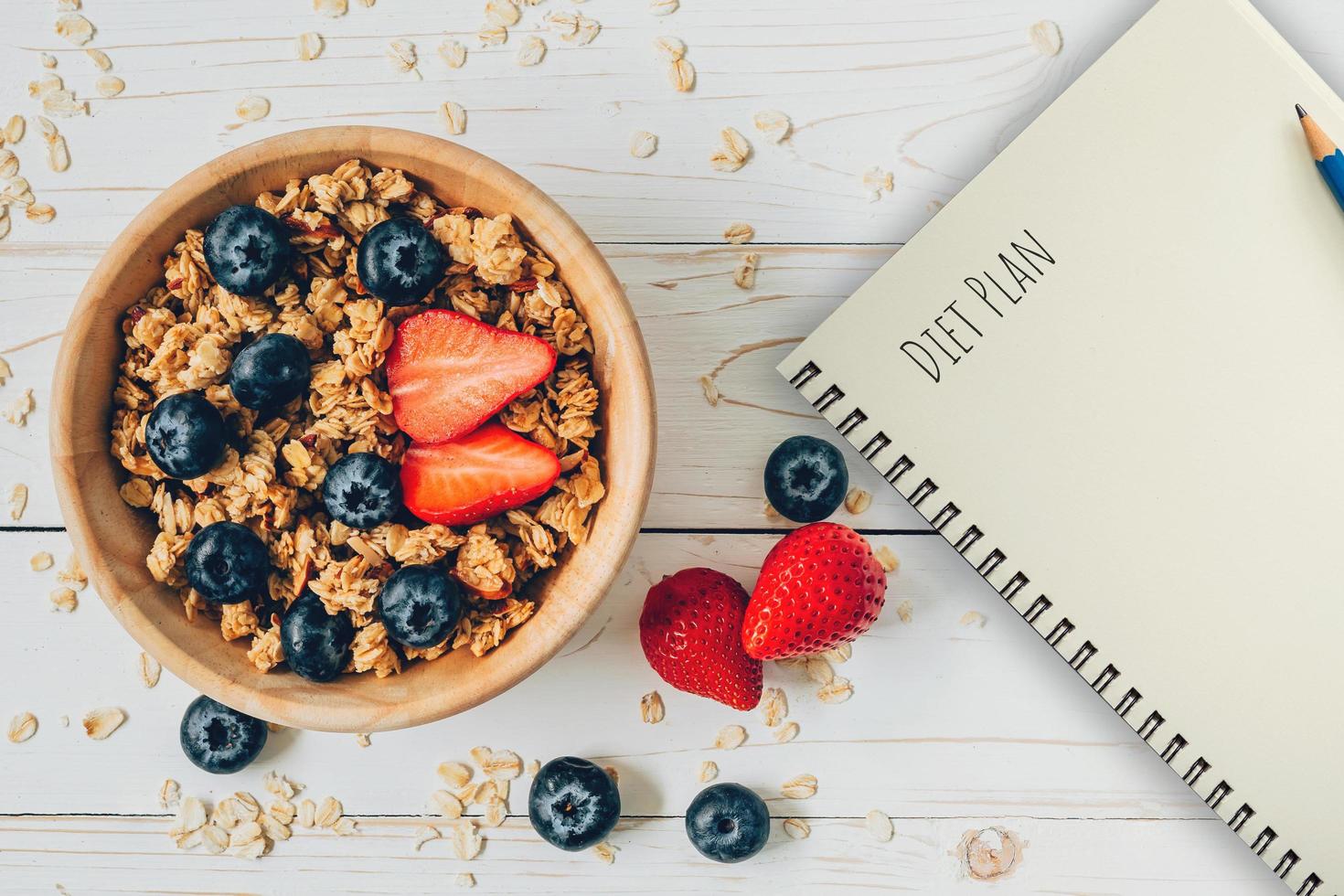 caseiro granola e fresco bagas em madeira mesa com Nota livro e texto dieta plano conceito, cópia de espaço. foto