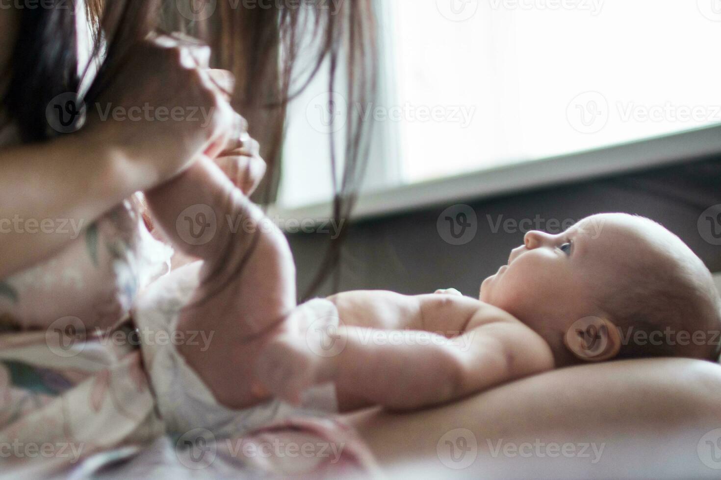 mãe com uma bebê em uma cama de a janela foto