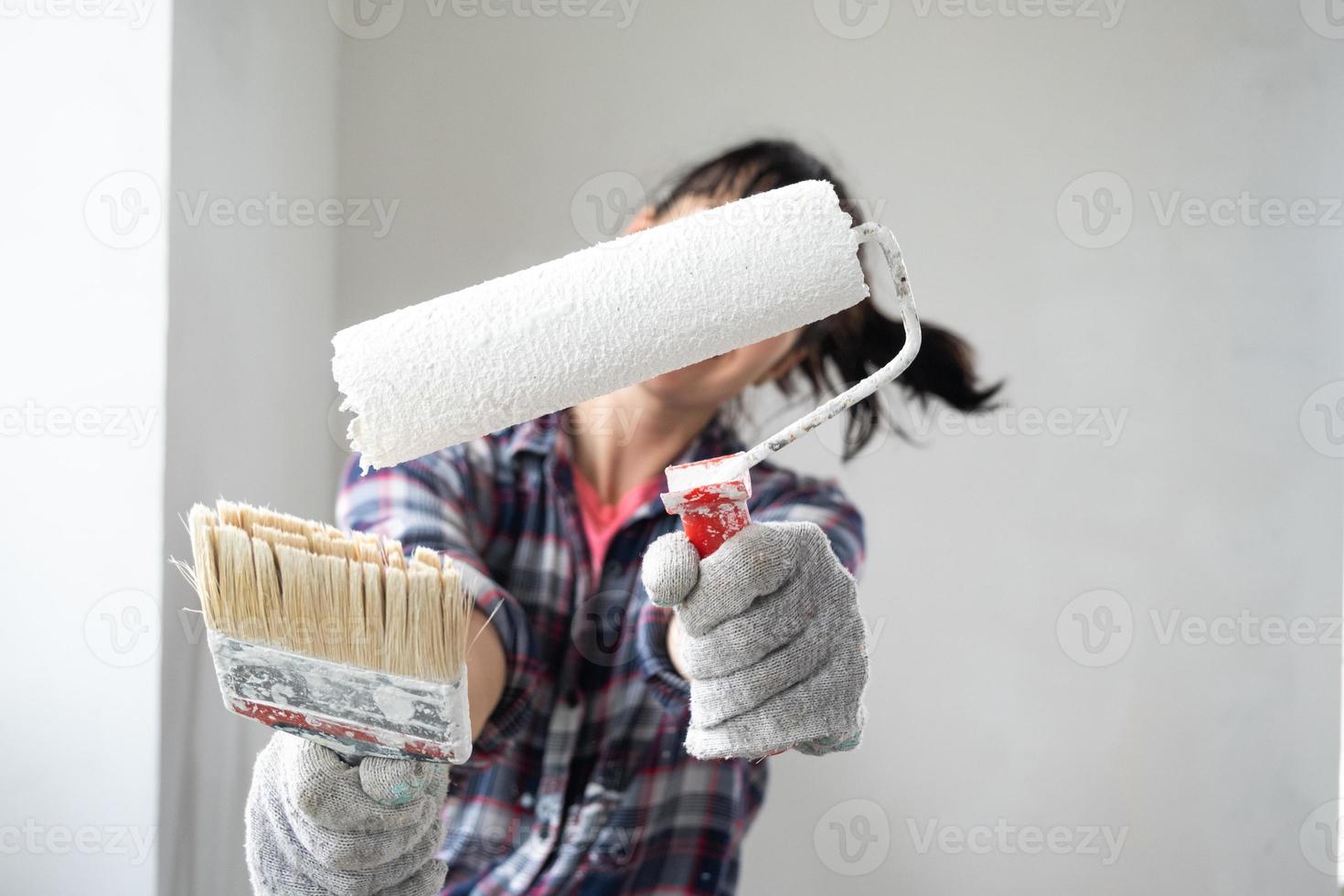 intrigado mulher dentro pintura rolo e branco pintura para paredes dentro mãos fechar-se retrato. construção trabalhos e Cosmético reparos dentro casa, parede pintura, tingimento, acabamento trabalhos com seu próprio mãos foto