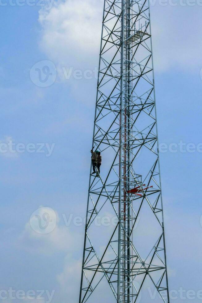 pintar antenas de celular e internet para realçar a beleza de jovens trabalhadores corpulentos com audácia de alcançar alturas é um trabalho perigoso. foto