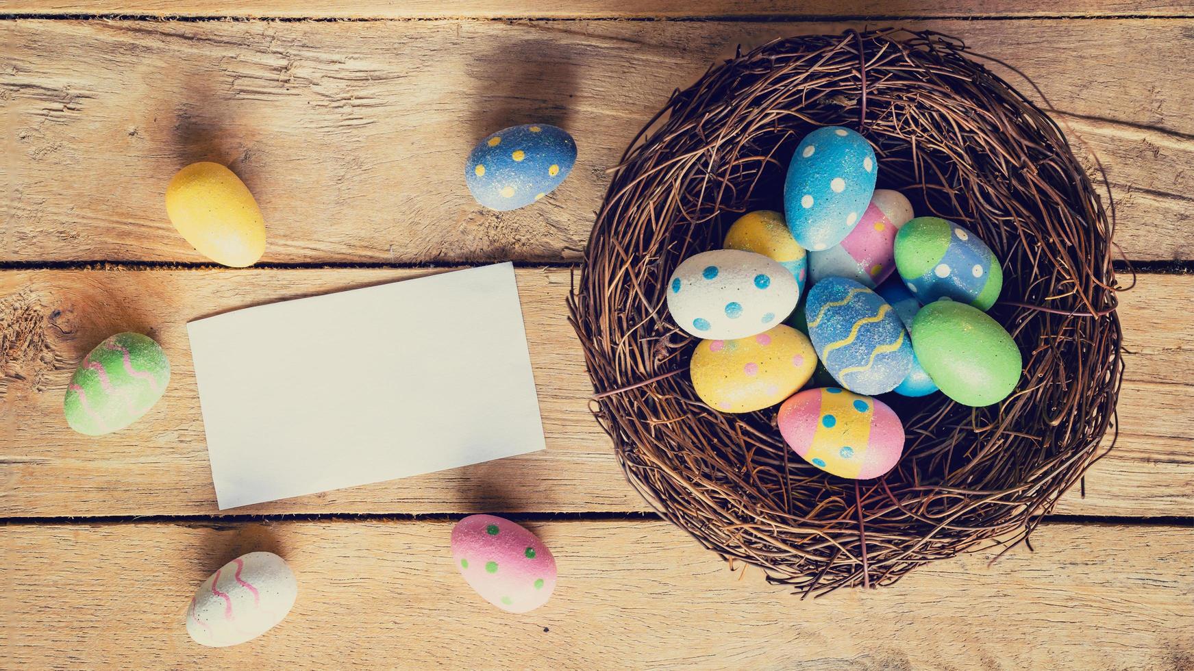 colorida Páscoa ovo dentro ninho e papel cartão em madeira fundo com espaço. foto