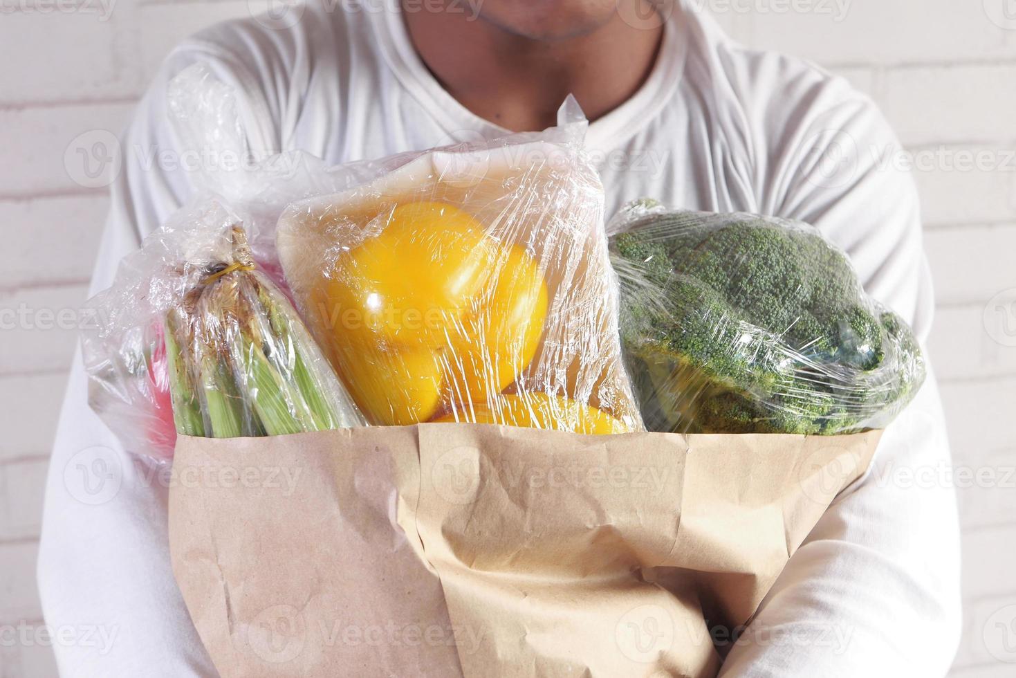 carregando vegetais em uma sacola marrom foto