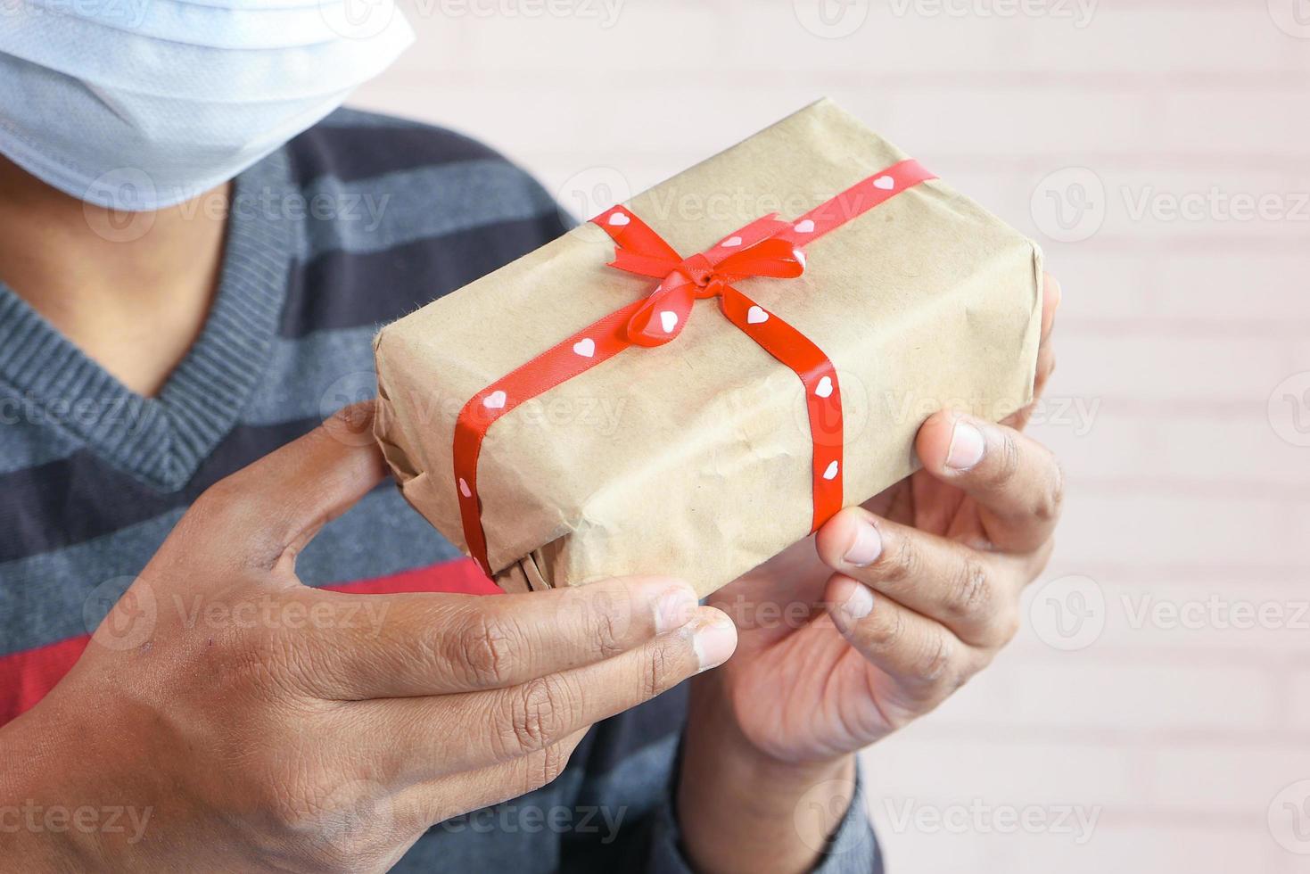 homem usando máscara segurando uma caixa de presente foto