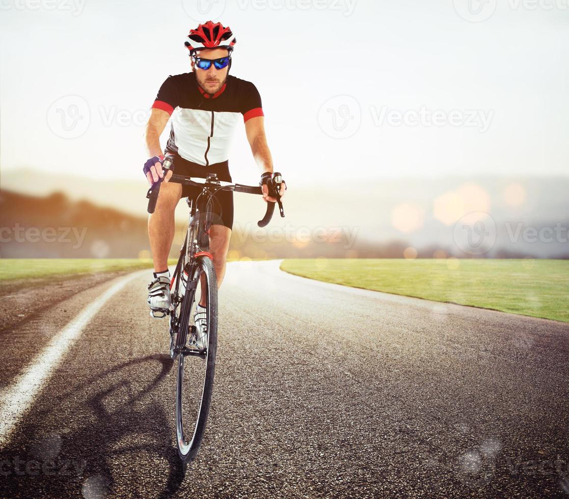 ciclista corrida em a estrada às pôr do sol foto