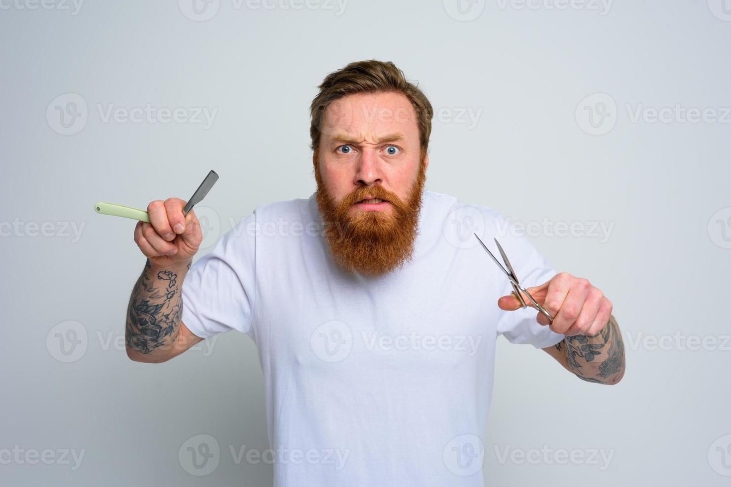 agressivo homem com tesouras e lâmina é pronto para cortar a barba foto