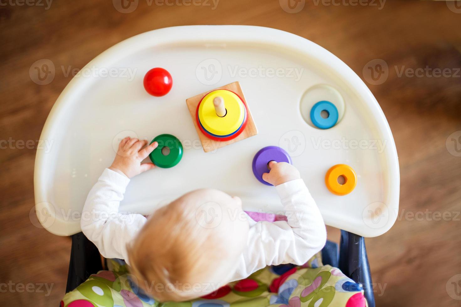 a criança tocam a pirâmide. criança dentro a crianças quarto jogando com brinquedos Visão a partir de acima foto