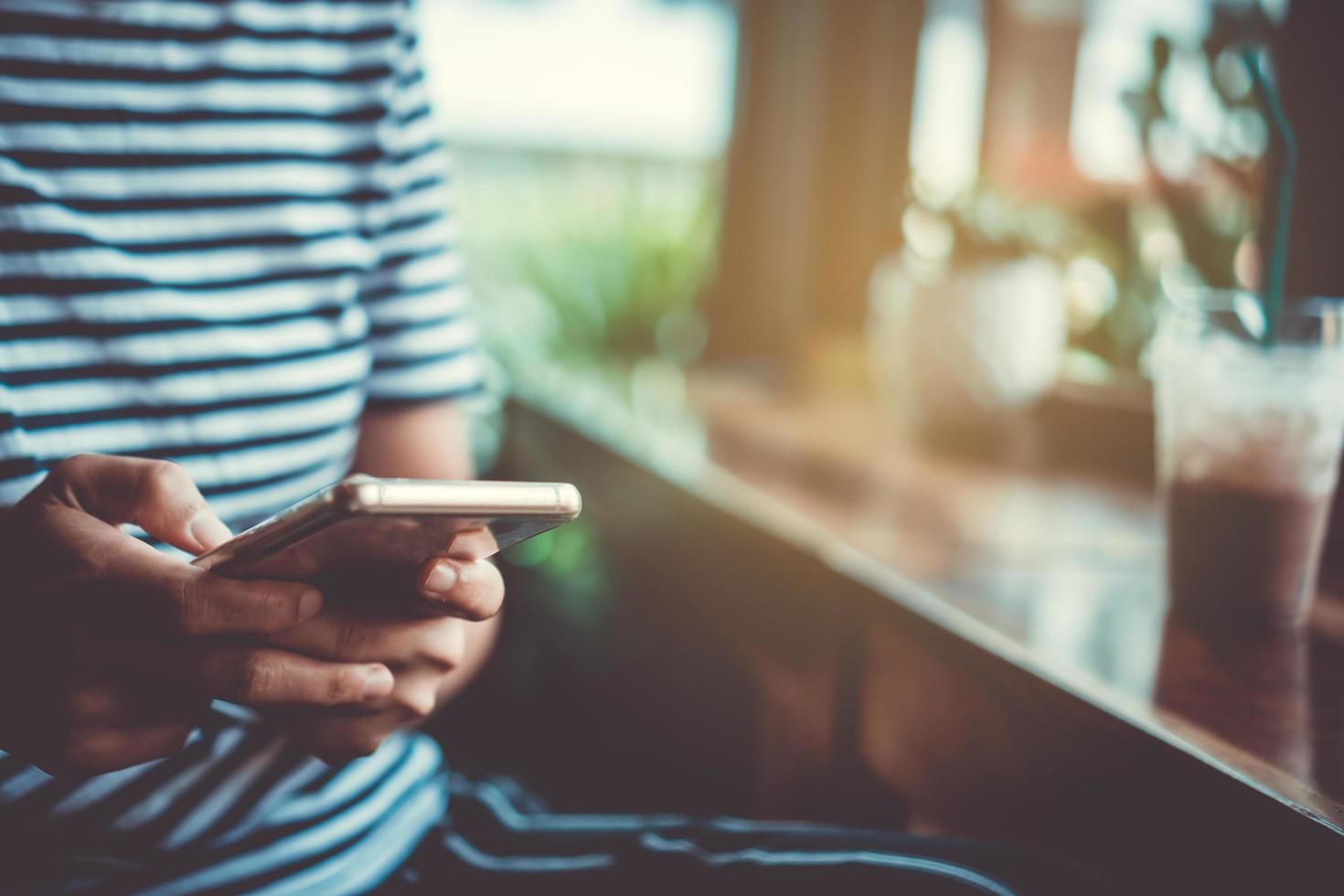 mulher usando um smartphone em uma cafeteria com luz solar foto