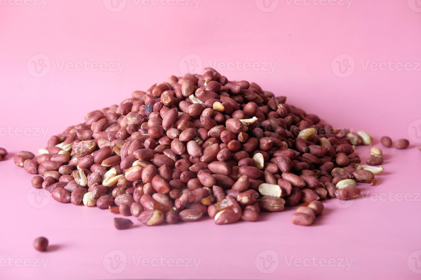pilha de amendoim em fundo rosa foto