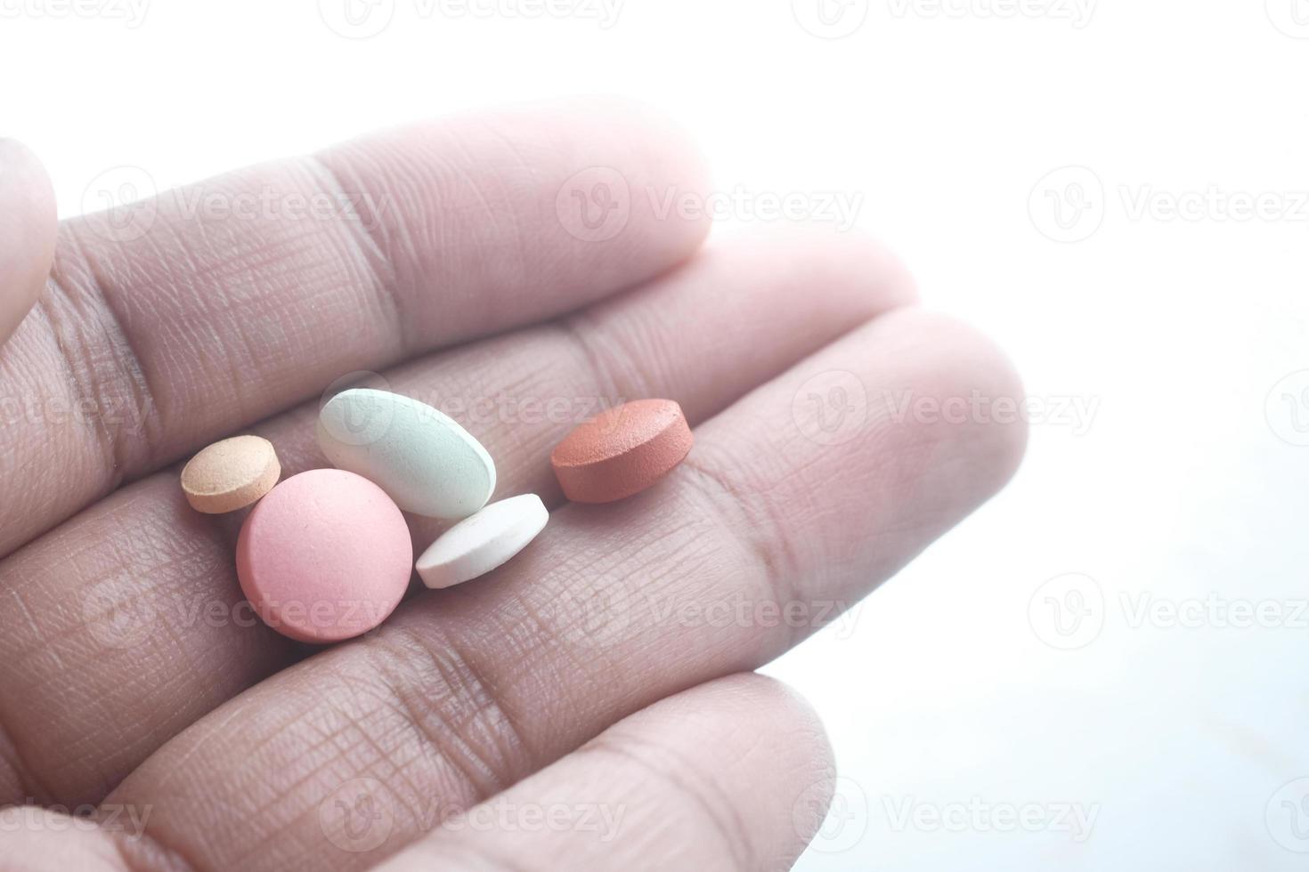 close-up de pílulas coloridas na mão isoladas em branco foto