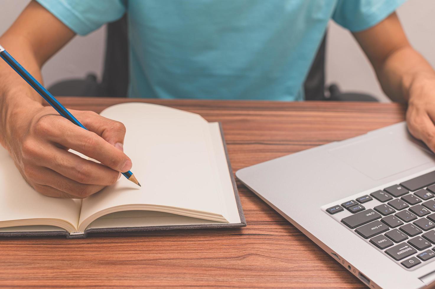 pessoa escrevendo um livro em uma mesa foto