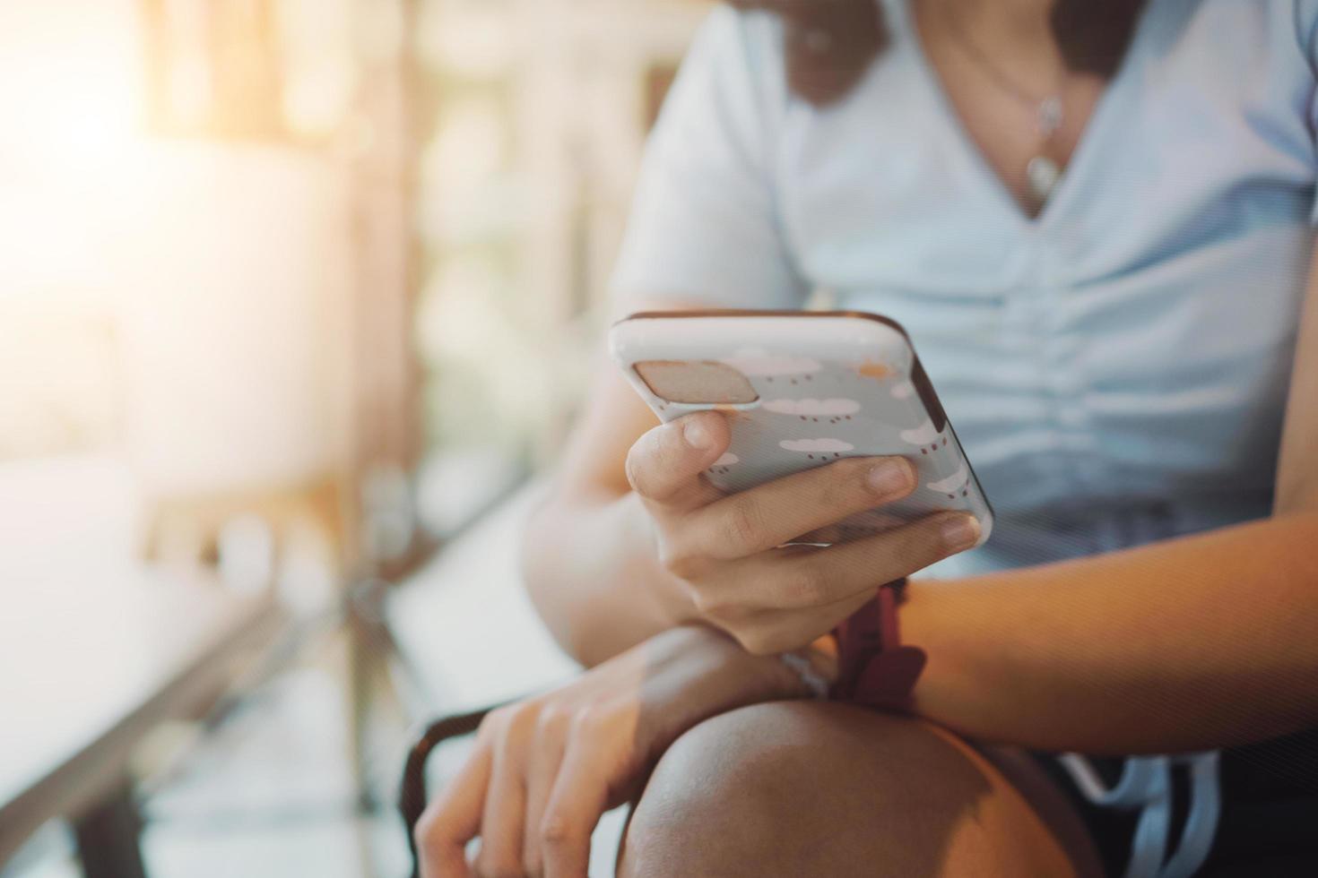 mulher usando um smartphone em uma cafeteria com luz solar foto