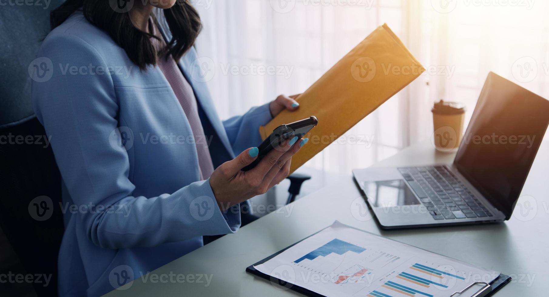 atraente sorridente jovem ásia o negócio mulher trabalhos às casa escritório, ásia mulher trabalhando em computador portátil computador segurando tábua. foto