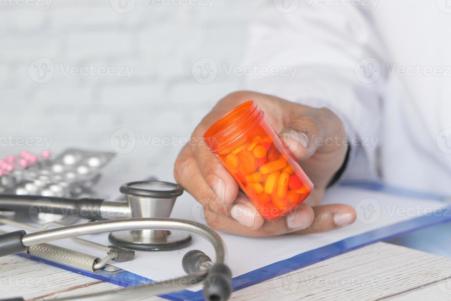 médico segurando o frasco de comprimidos foto
