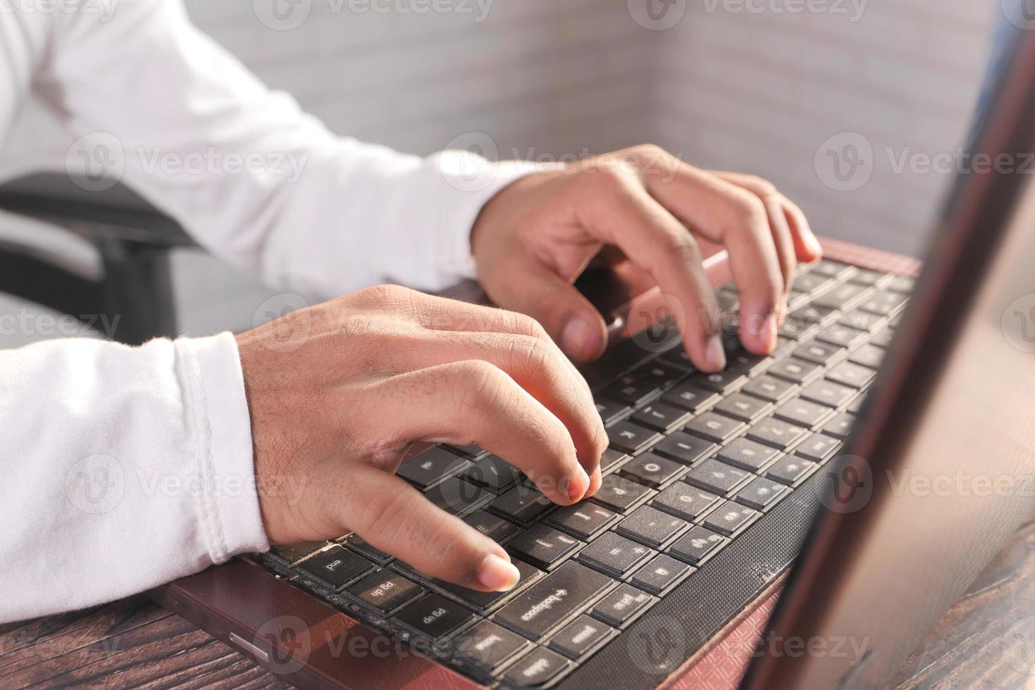 perto da mão do homem digitando no laptop foto