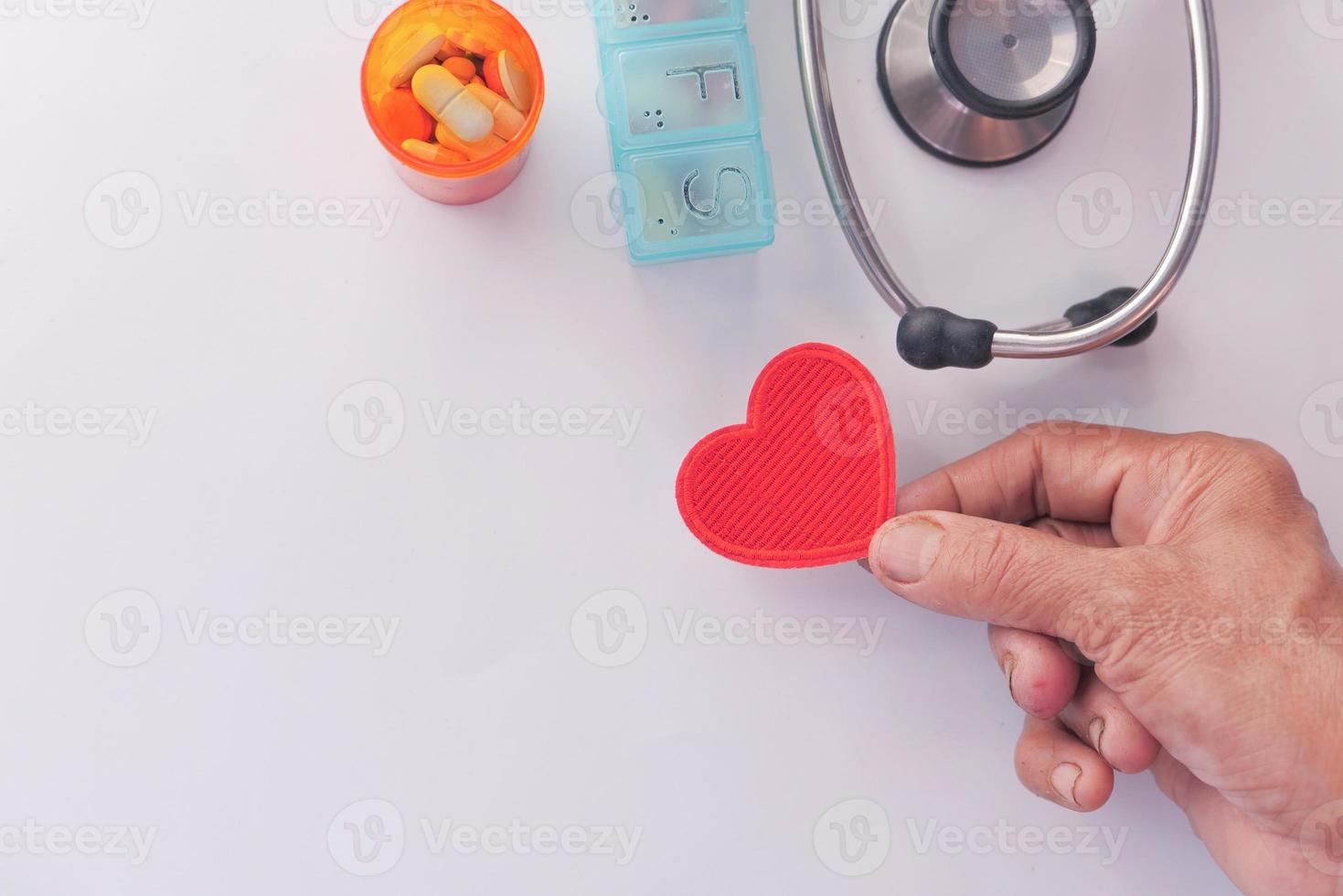 segurando um coração vermelho com suprimentos médicos foto