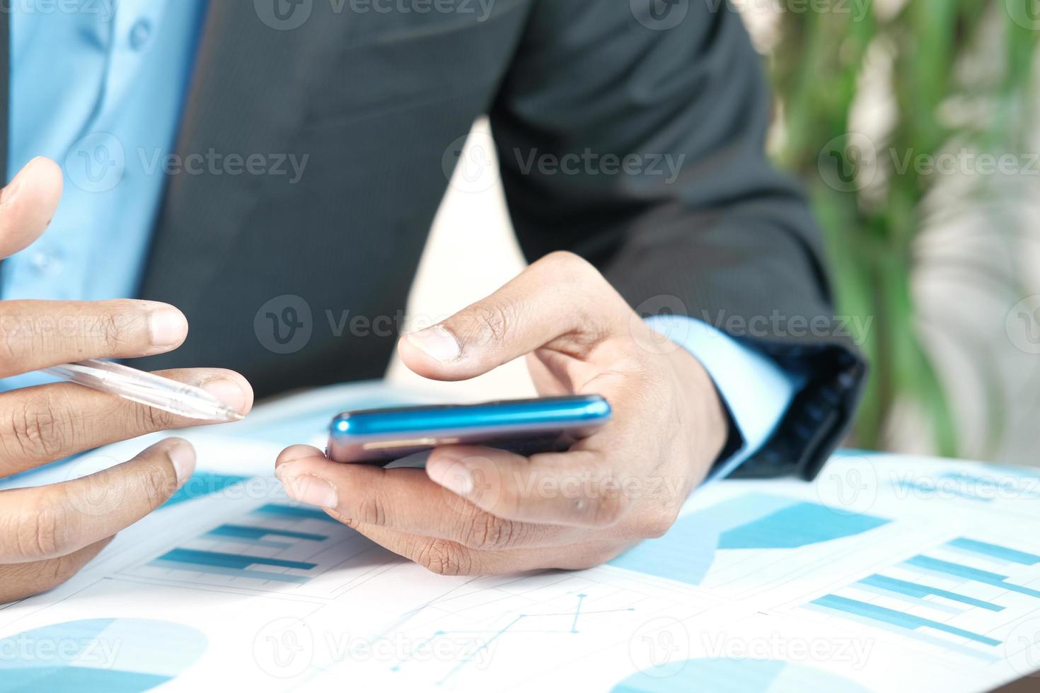 empresário usando telefone inteligente enquanto trabalha na mesa foto