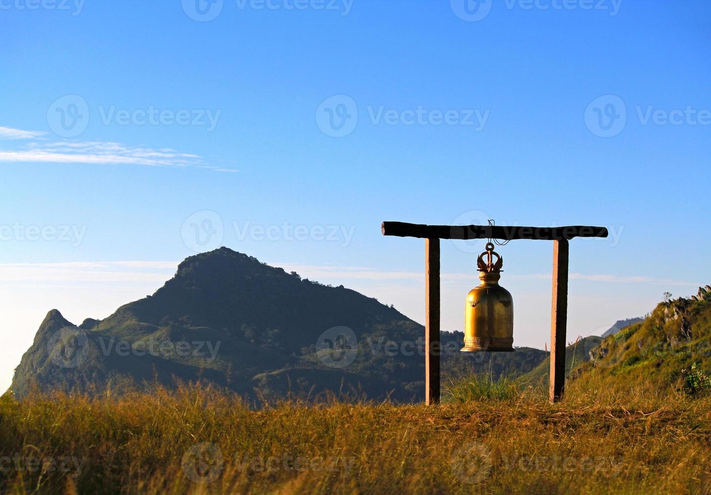 a dourado ou ouro antigo Sino suspensão em Alto Lugar, colocar com montanha e Claro azul céu fundo com cópia de espaço. lindo objeto decoração com panorama Visão do natureza. ponto de referência em ponto de vista foto