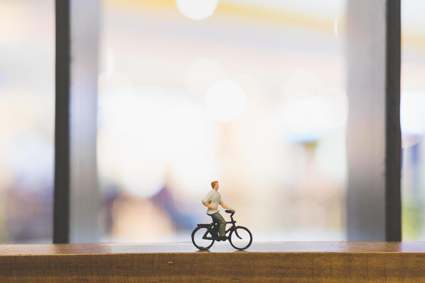 viajante em miniatura com uma bicicleta em uma ponte de madeira foto