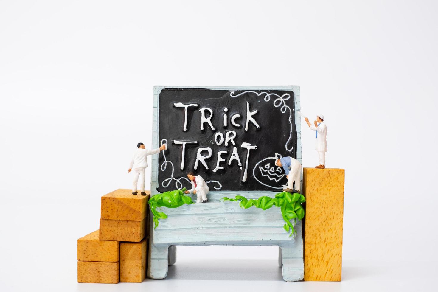 pessoas em miniatura colorindo decorações de adereços de festa de halloween em um fundo branco, conceito de festa de halloween foto