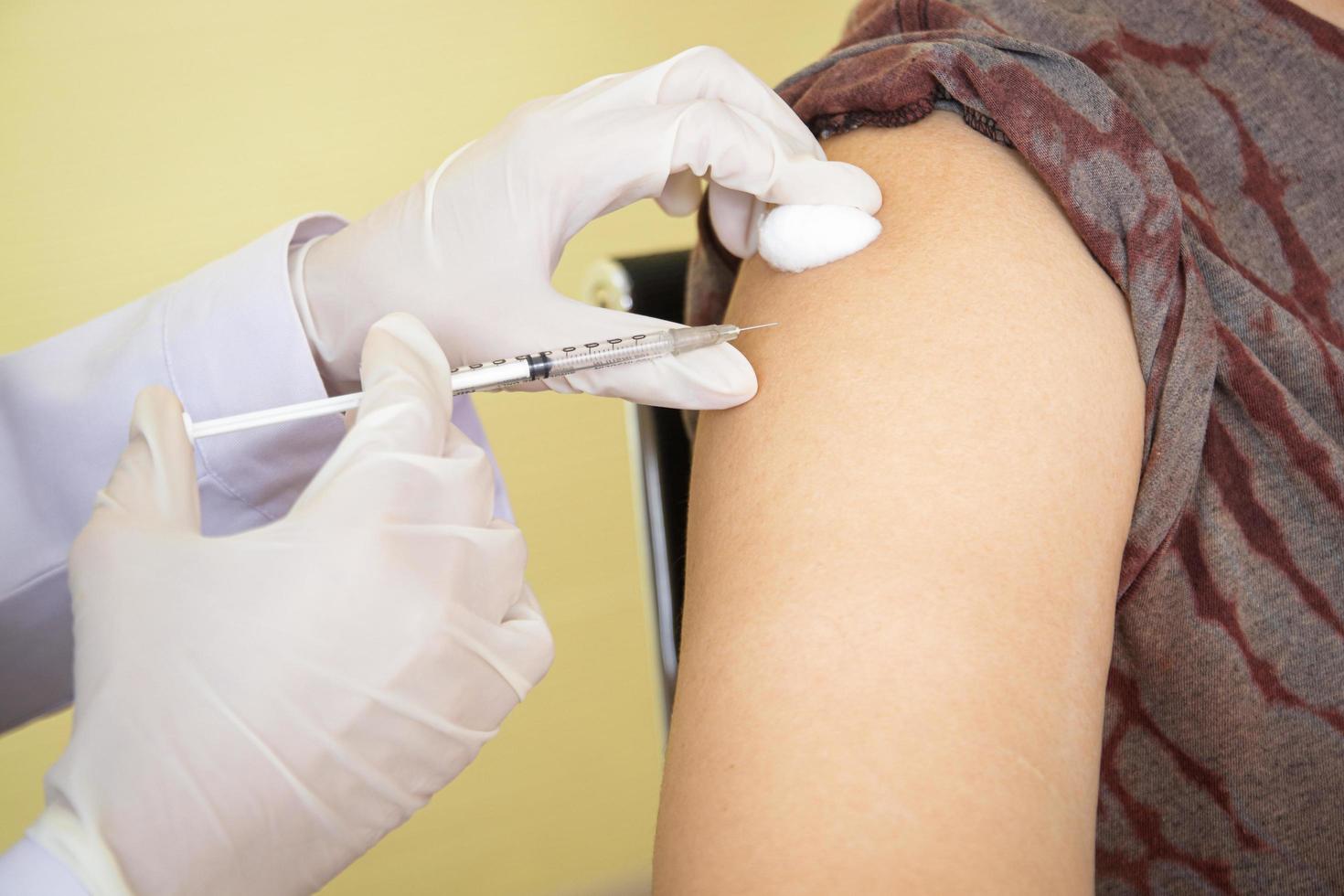uma fêmea médico injetado a coronavírus covid-19 vacina para uma gordo homem dentro a superior certo braço. conceito do médico serviço dentro a hospital. antiviral vacina foto