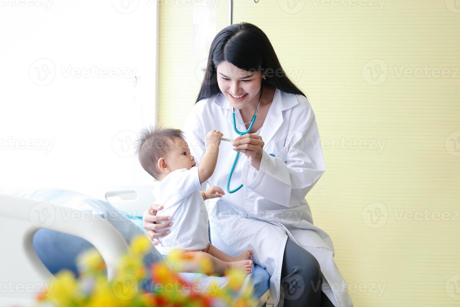 fêmea médico examina a ásia pequeno Garoto paciente dentro cama dentro uma clínica. saúde Cuidado conceito foto