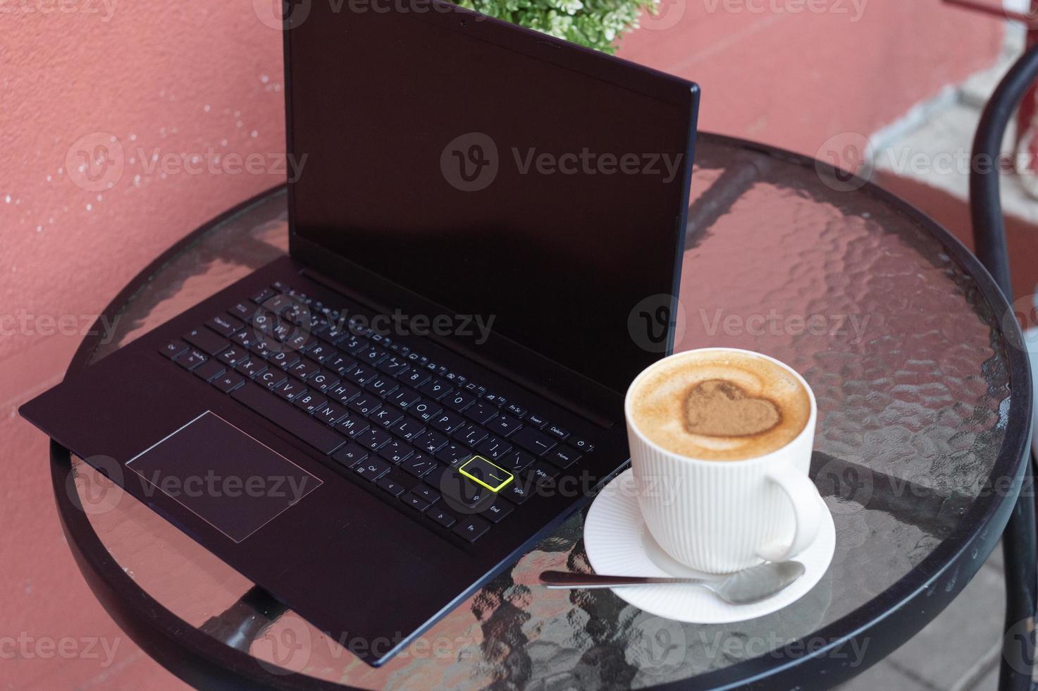 computador portátil com uma copo do café em a terraço foto