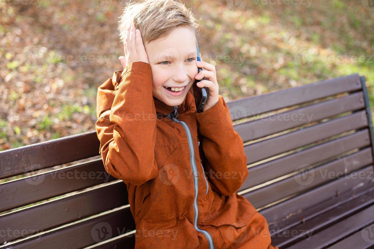 a emocional Garoto é falando em a telefone segurando dele cabeça e rindo foto