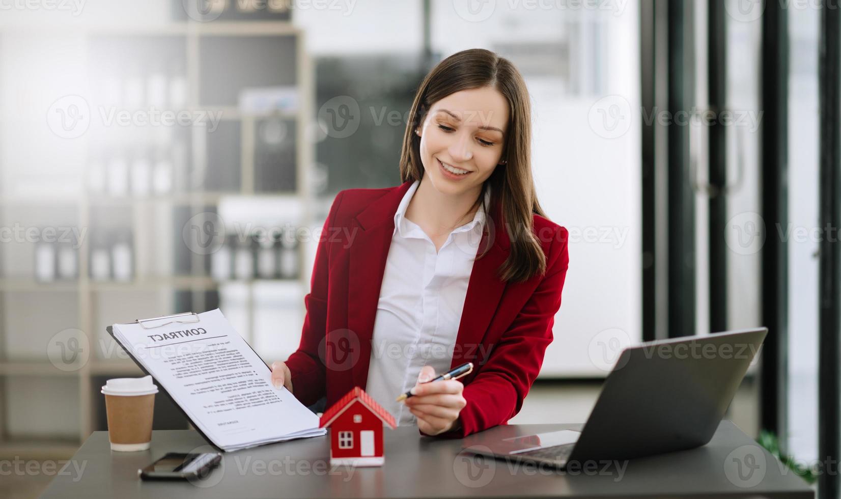 real Estado agente trabalhador trabalhando com computador portátil e tábua às mesa dentro escritório e pequeno casa ao lado isto. foto