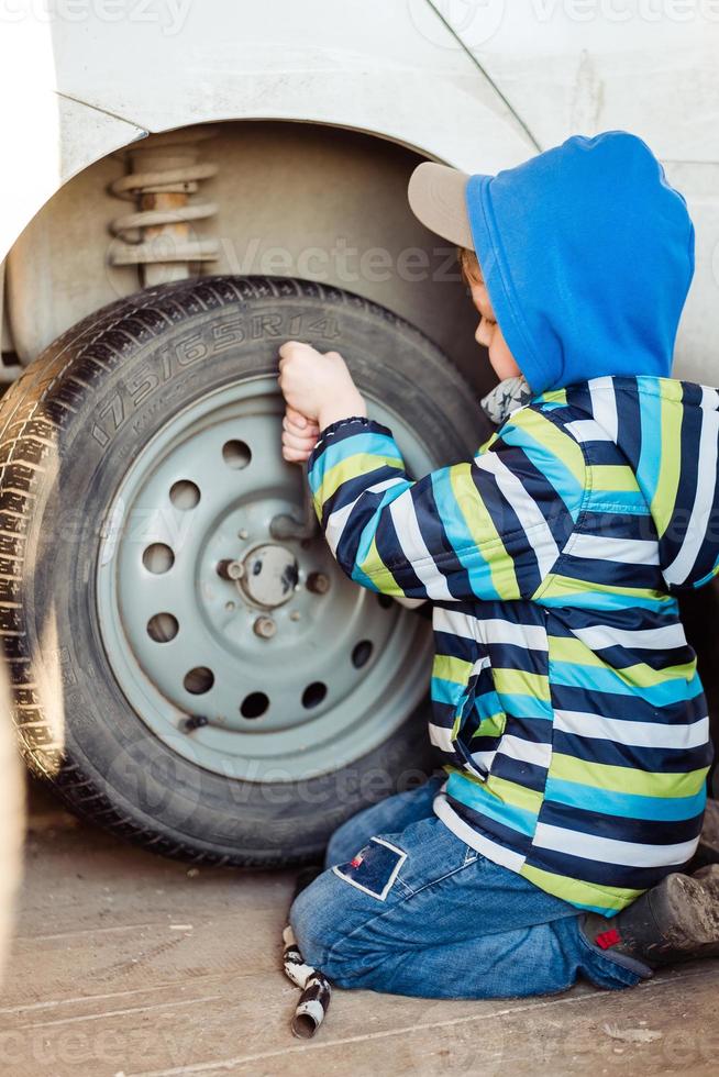a criança é reparação a carro. a Garoto é mudando a roda. foto