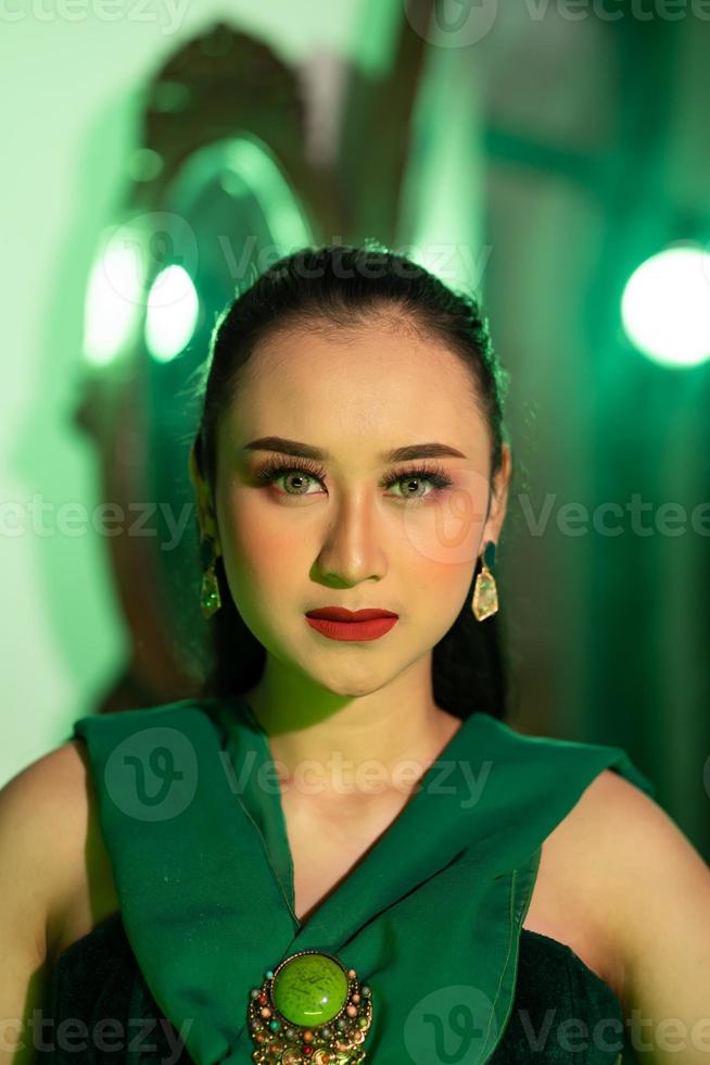 uma lindo ásia mulher dentro uma verde vestir tem uma muito exótico face com orelha e corpo joalheria enquanto foto
