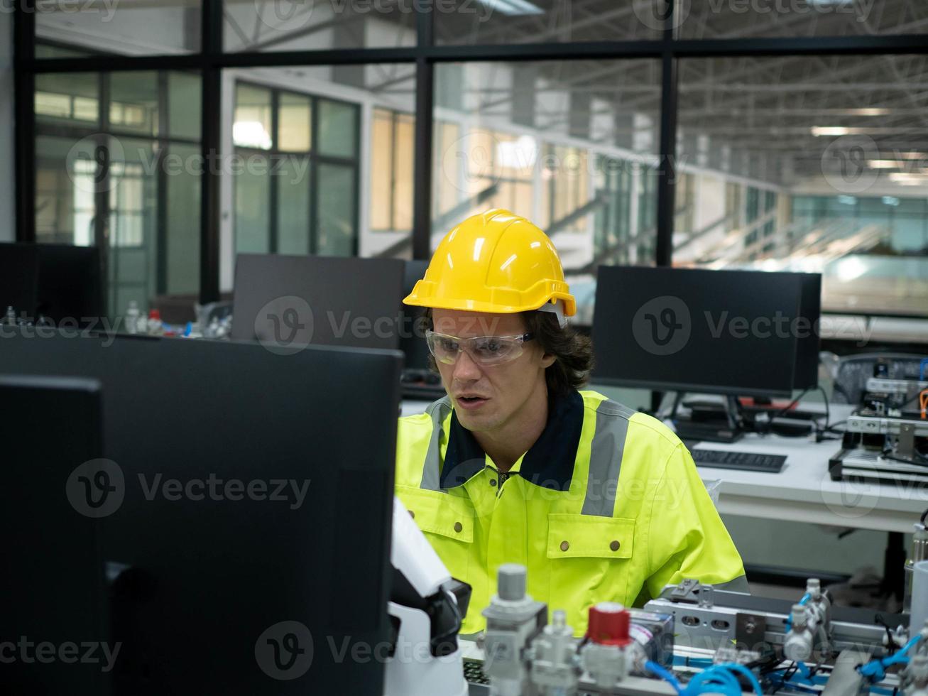 homem pessoa amarelo laranja cor uniforme vestem óculos fábrica sentado trabalhos trabalho ocupação computador caderno tecnologia indústria eletrônico robô manutenção engenheiro construção fabricação produtos foto