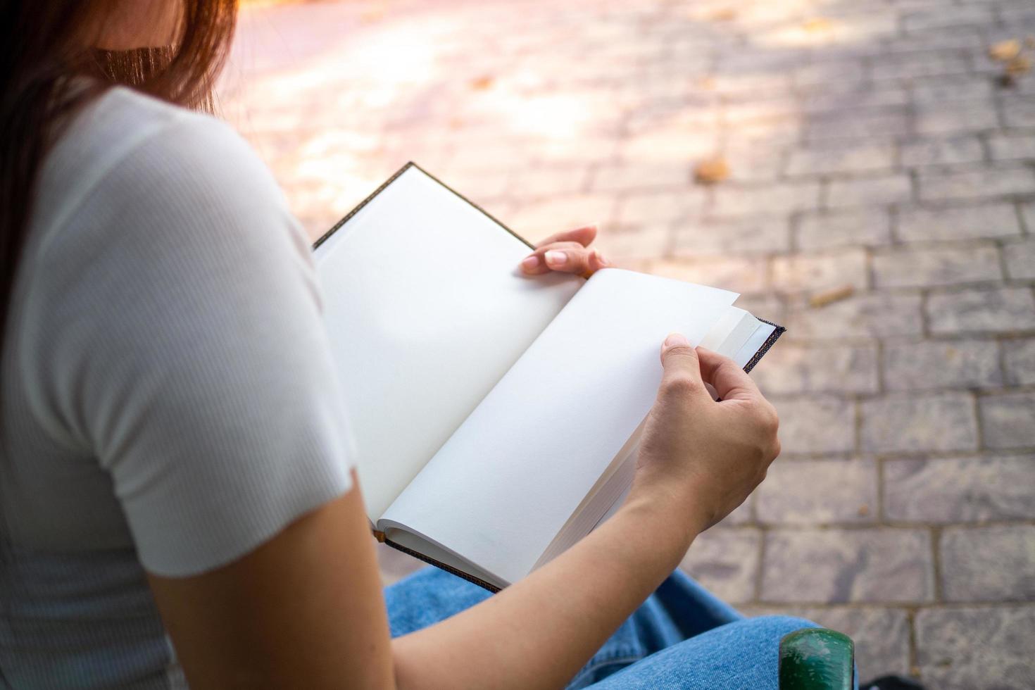 uma mulher é lendo uma livro dentro a parque. Aprendendo e diligentemente procurando conhecimento todos a tempo. foto