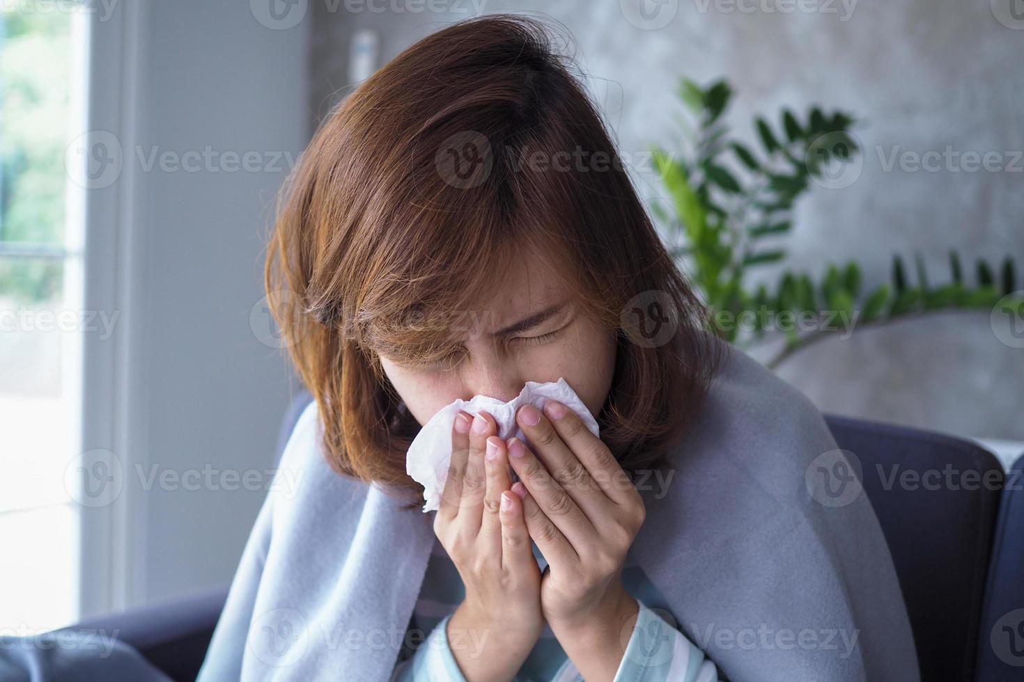 ásia mulheres ter escorrendo nariz e pegar uma frio, tosse, espirros, febre, sentado doente em a sofá dentro a casa. foto