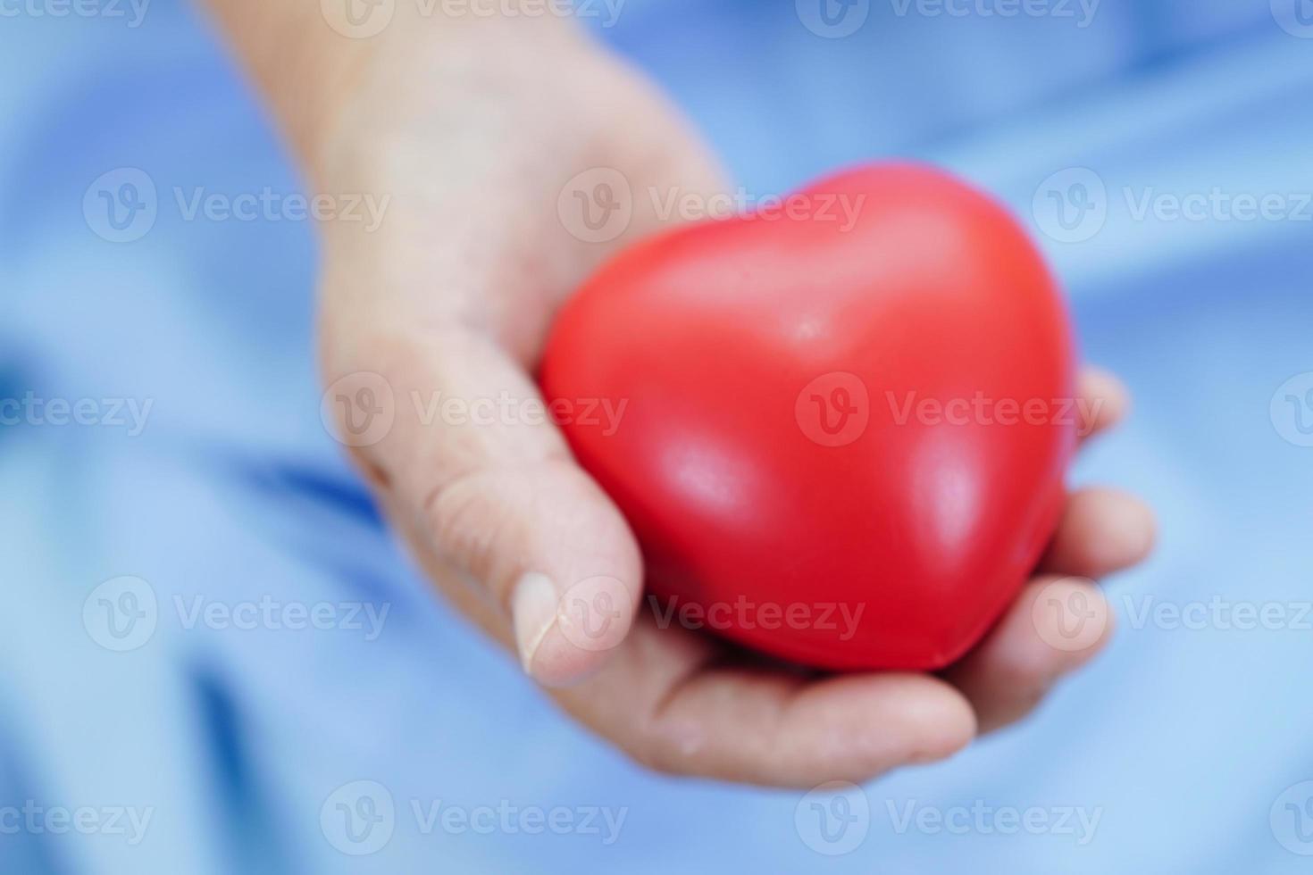 paciente asiática idosa idosa segurando coração vermelho no hospital. foto