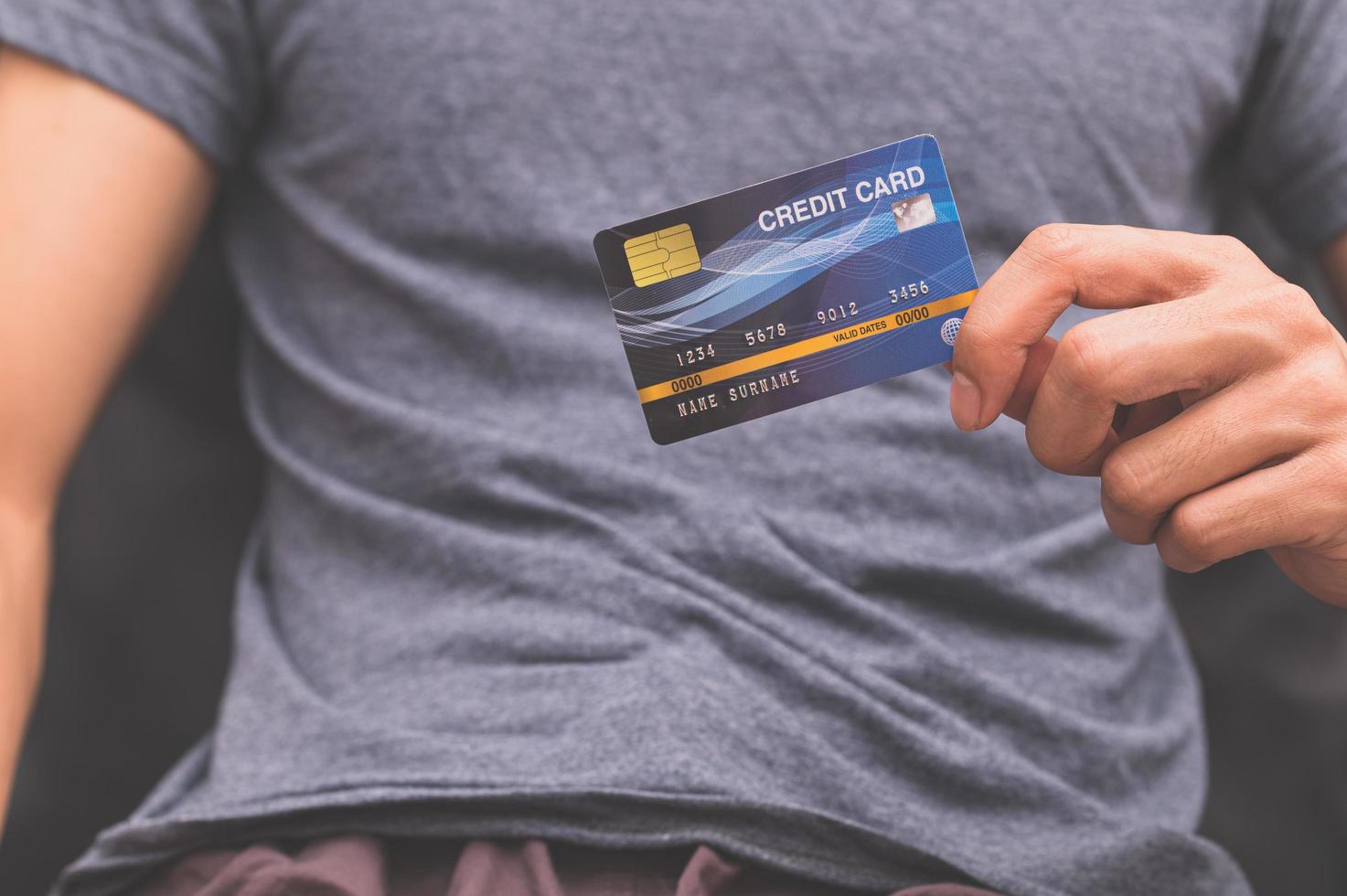 um homem segurando um cartão de crédito na mão foto