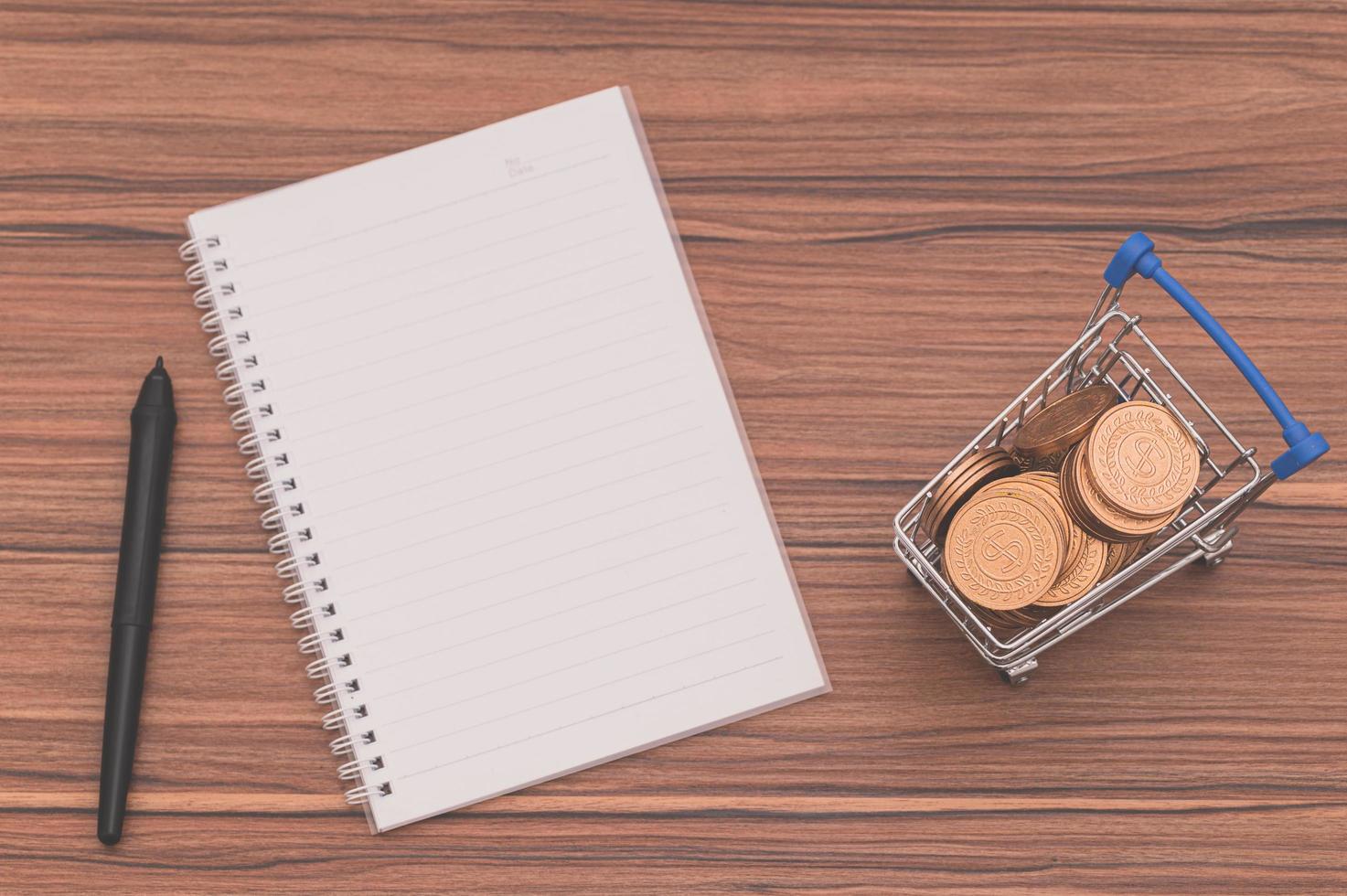 caderno na mesa com moedas em um carrinho minúsculo foto