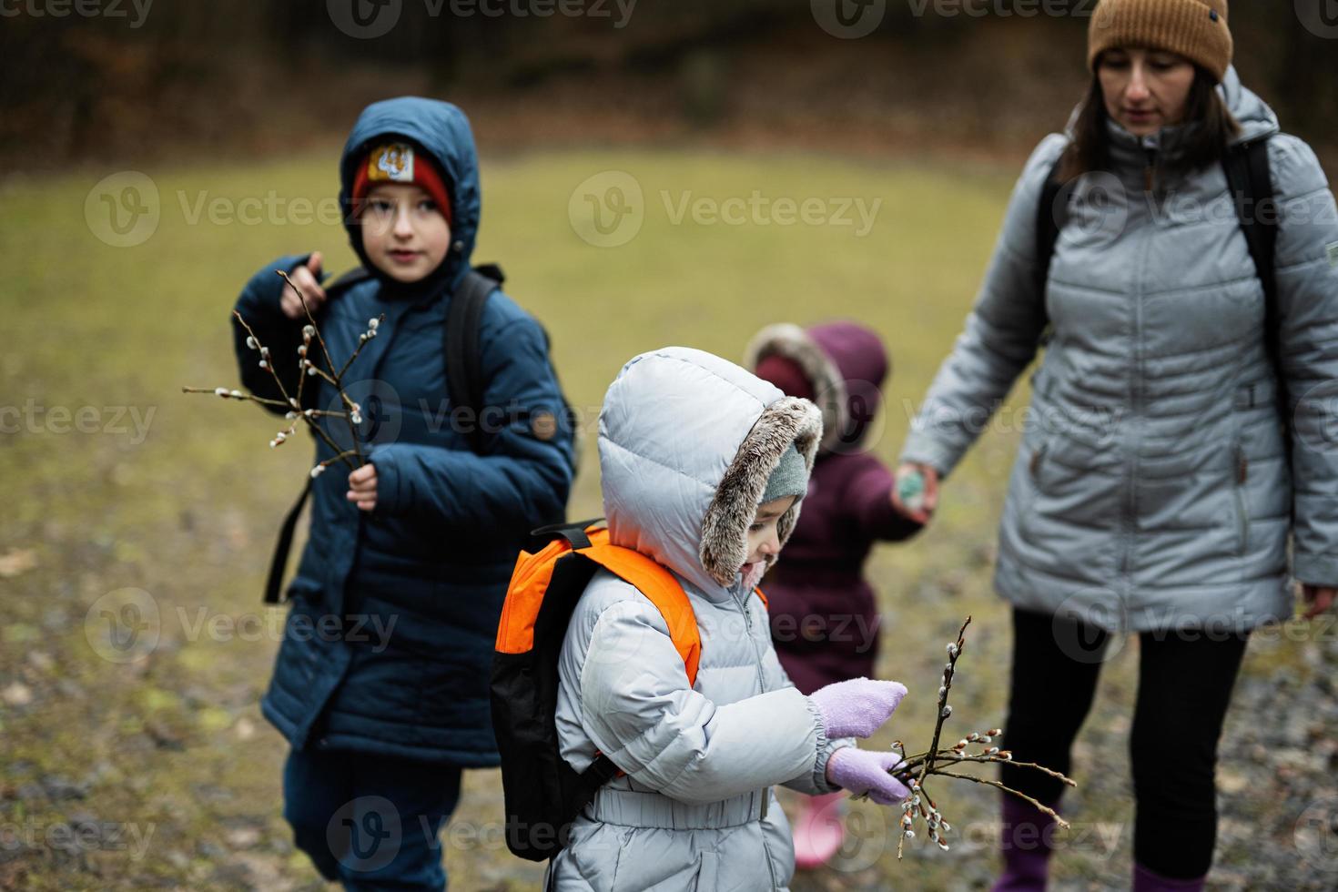 mãe com crianças segurando salgueiro galhos enquanto viajando dentro floresta. foto