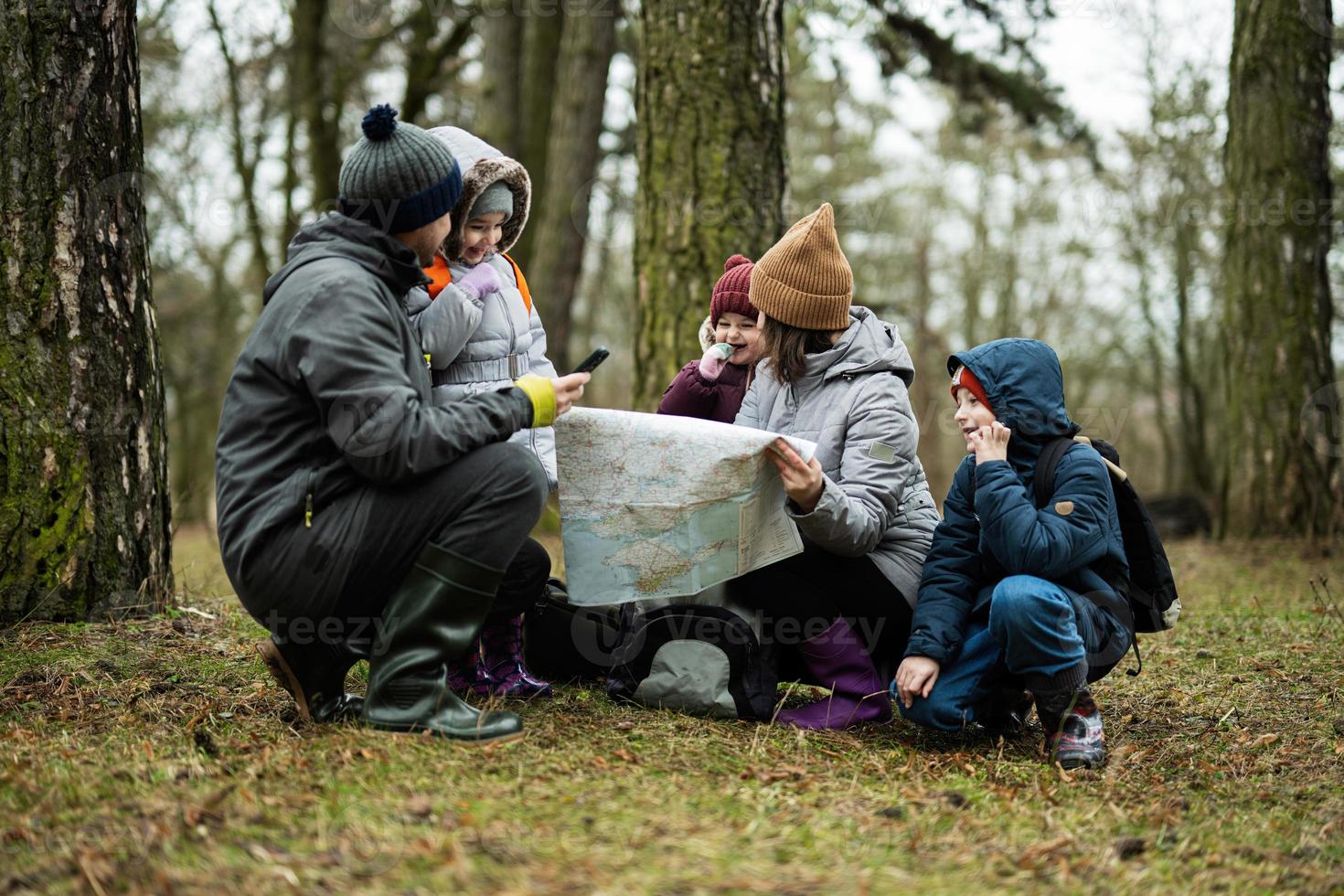 família e crianças com mapa dentro a floresta. foto