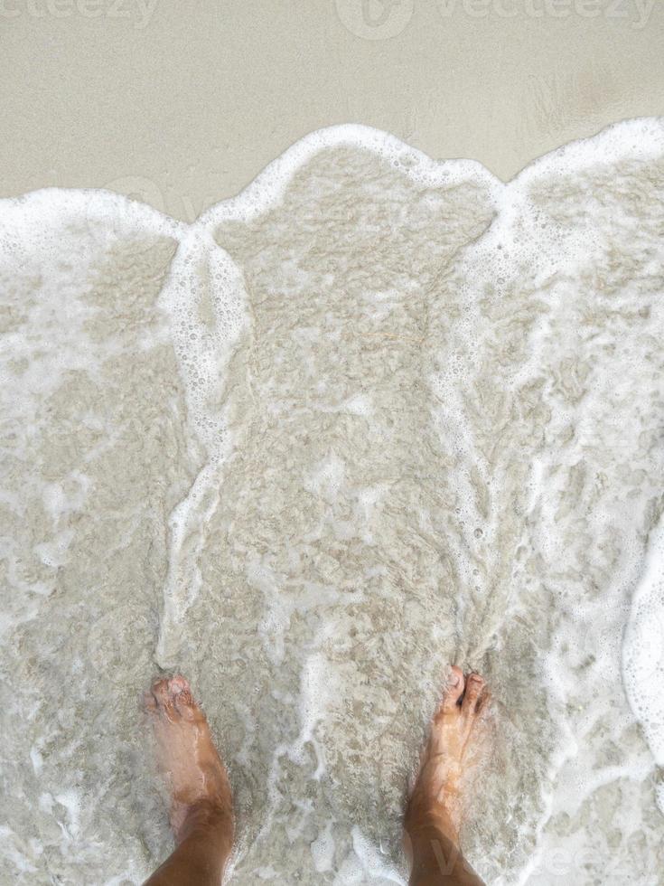 a descalço em a de praia com a branco espuma a partir de a aceno. foto
