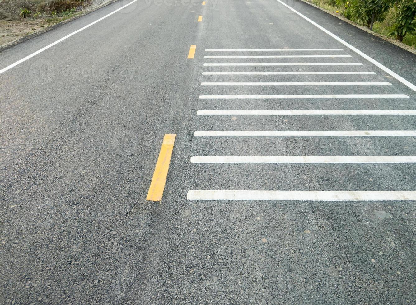 a branco transversal Estrondo tiras em a asfalto estrada. foto