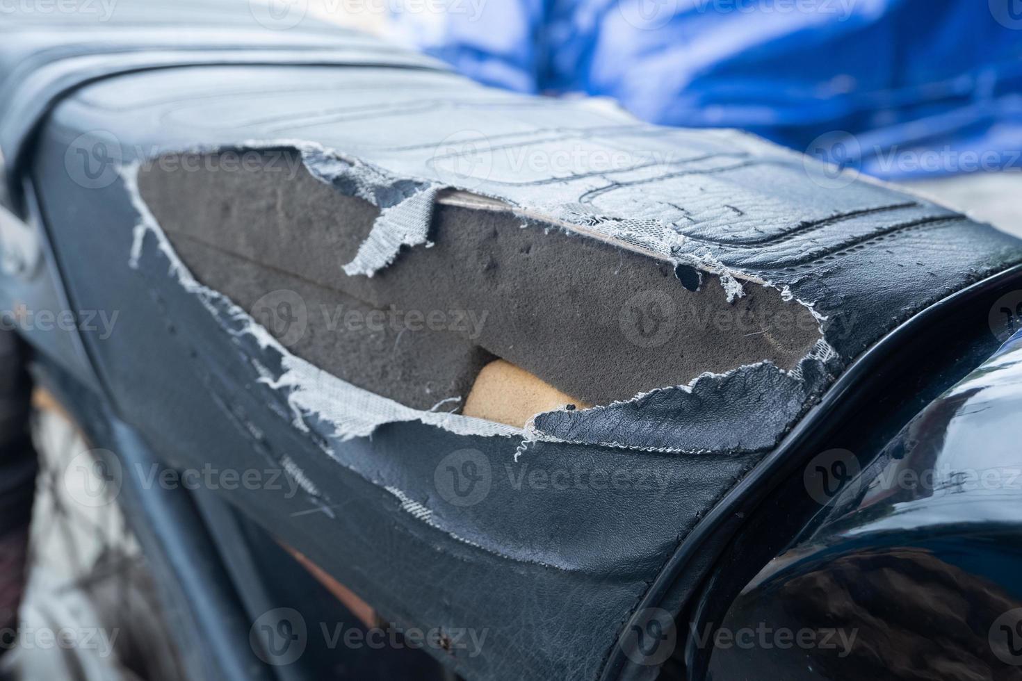 seletivo fokus em a lacerado motocicleta assento , velho Preto couro assento é danificar , quebrado couro. foto