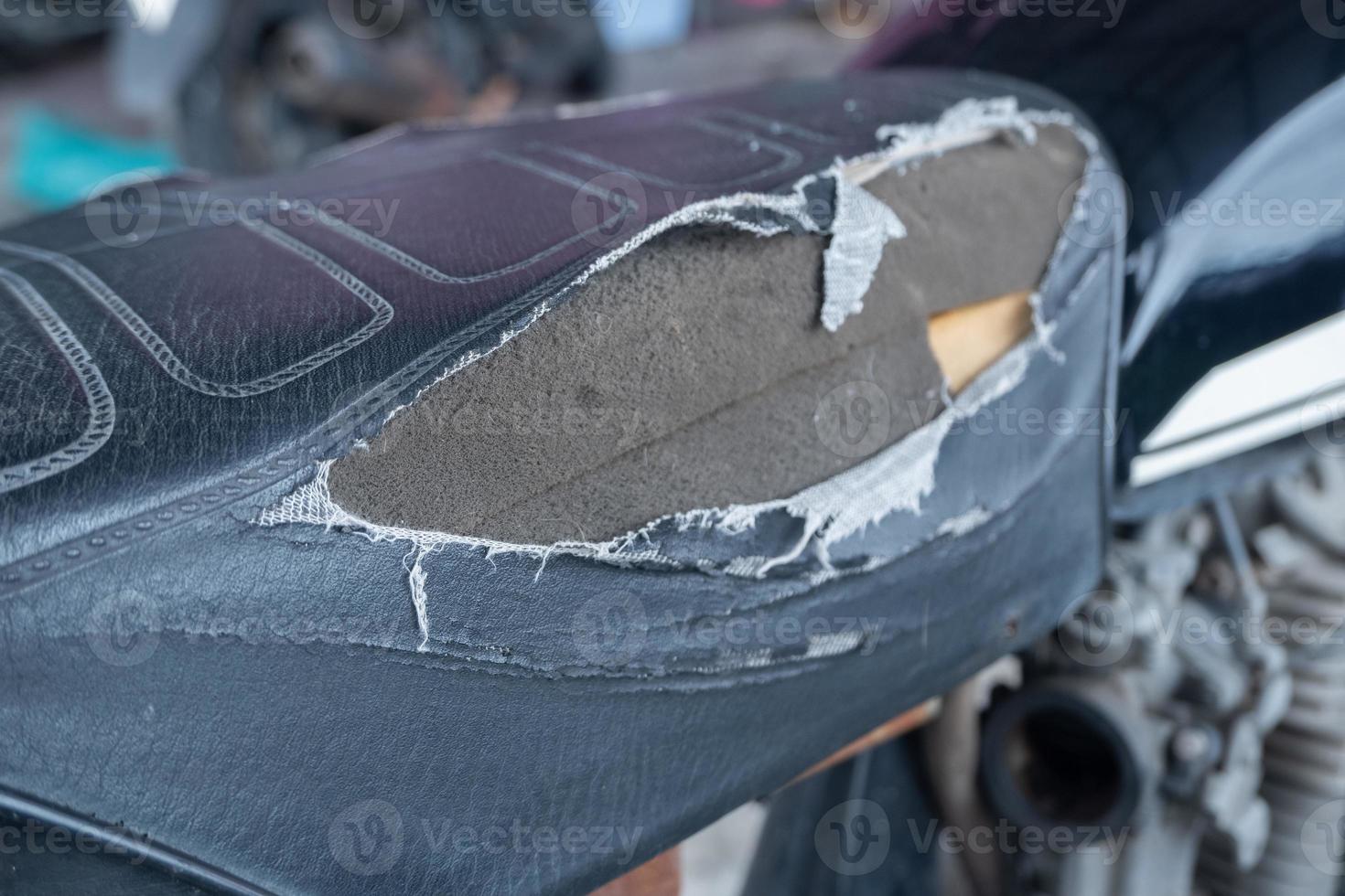 seletivo fokus em a lacerado motocicleta assento , velho Preto couro assento é danificar , quebrado couro. foto